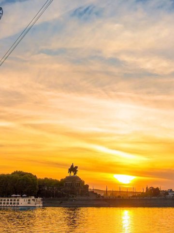 Abendstimmung am Deutschen Eck in Koblenz – Sonnenuntergang über dem Rhein mit Kaiserdenkmal, Seilbahn und Ausflugsschiffen, goldene Spiegelung im Wasser