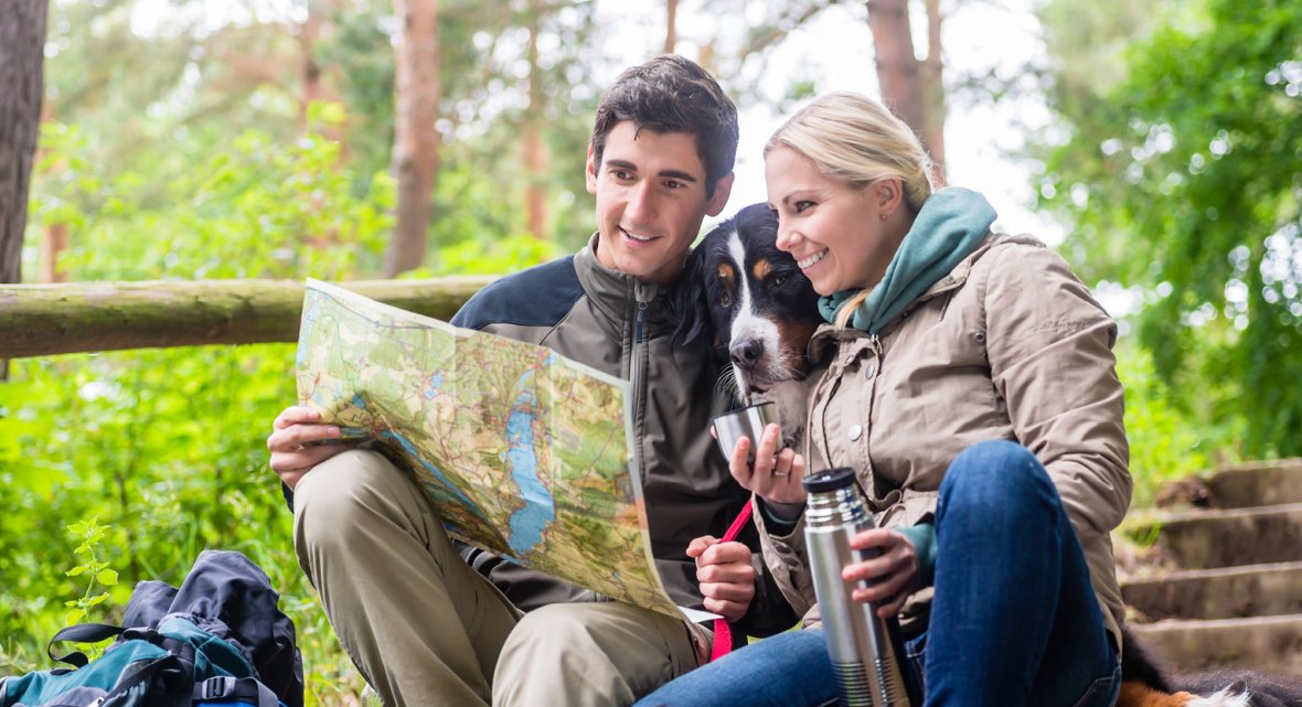 Break during a hike in the Westerwald near Schloss Montabaur Hiking in the Westerwald – two people sitting on a wooden bench in the forest, looking at a hiking map and drinking from a thermos, surrounded by green foliage and nature during a short break at Schloss Montabaur