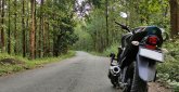 Motorradtour durch den Westerwald nahe Schloss Montabaur Schwarzes Motorrad steht auf einer schmalen Asphaltstraße, die durch einen dichten grünen Wald führt, umgeben von hohen Bäumen und Natur beim Kurzurlaub im Schloss Montabaur