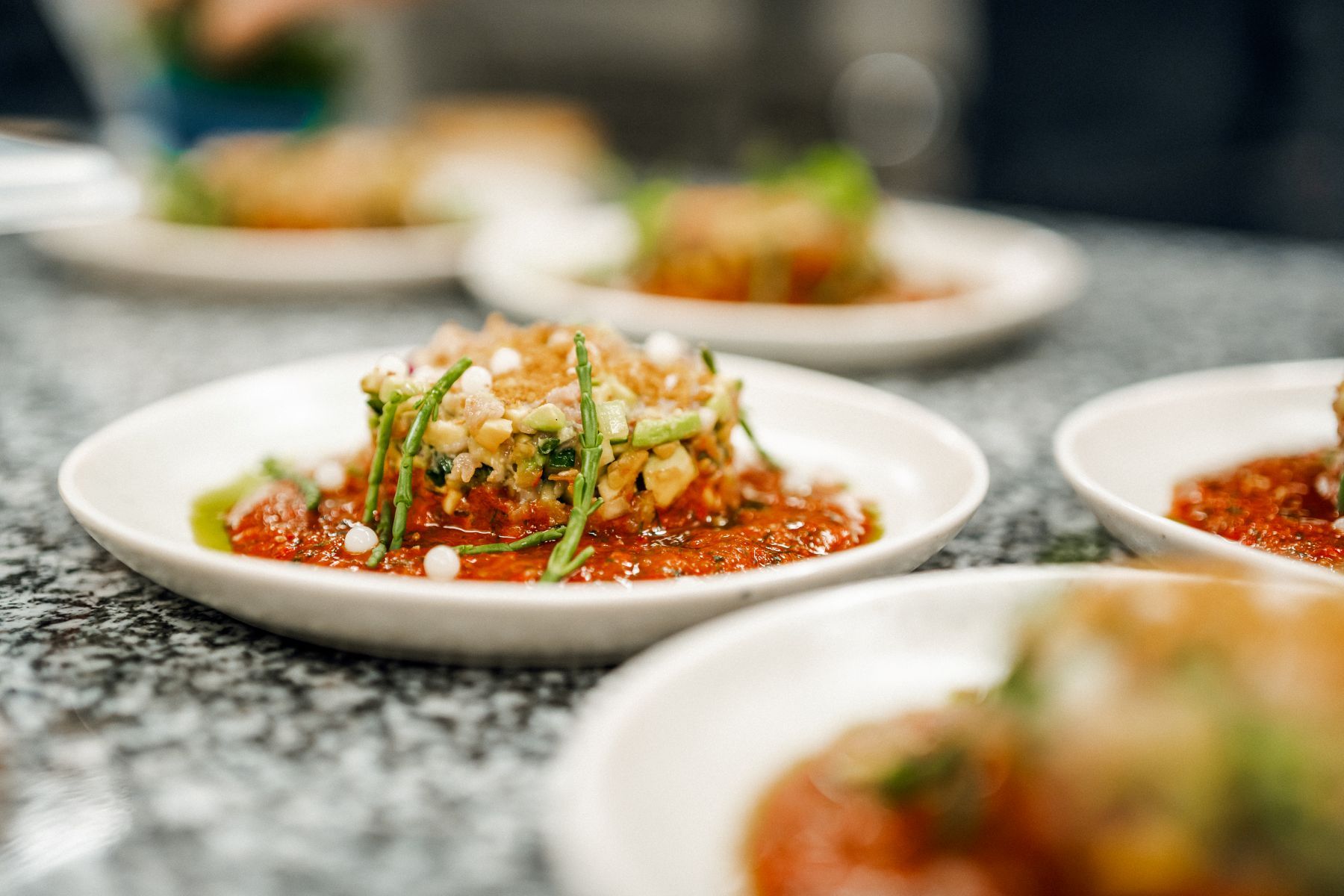 Kochkurs im Schloss Montabaur Servierter Teller mit Hauptgericht des Beispielmenüs: gebratenes Gemüse, cremiges Risotto und Kräuteröl, stilvoll angerichtet.