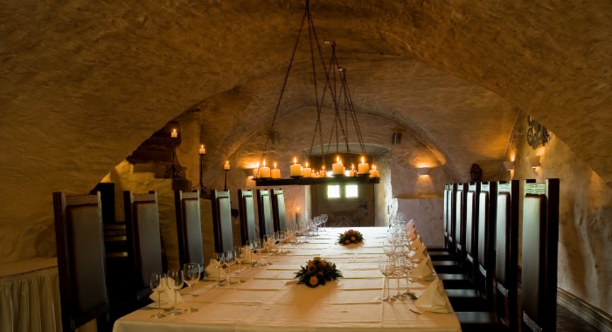 Atmospherically lit vaulted cellar in Hotel Schloss Montabaur with a festively laid table for up to 18 guests