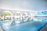 Moderner Innenpool im Spa des Hotels Schloss Montabaur mit großen Rundbogenfenstern und entspannender Atmosphäre.