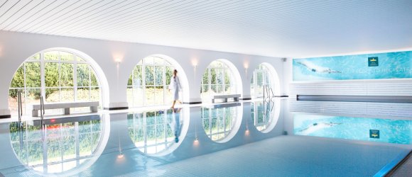 Innenpool Spa – Hotel Schloss Montabaur Moderner Innenpool im Spa des Hotels Schloss Montabaur mit großen Rundbogenfenstern und entspannender Atmosphäre.