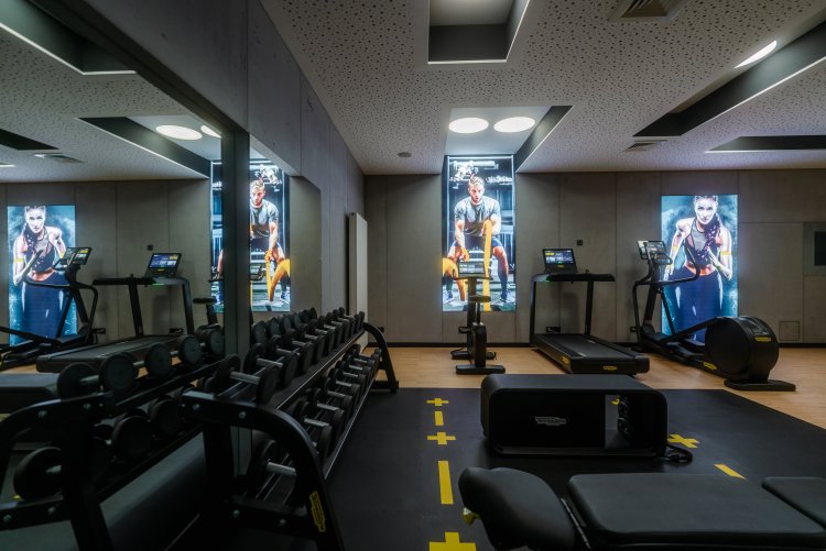 Premium-Fitnessbereich – Hotel Schloss Montabaur Fitnessbereich im Hotel Schloss Montabaur mit Laufbändern, Hantelbank, Spiegelwand und digitalen Displays.