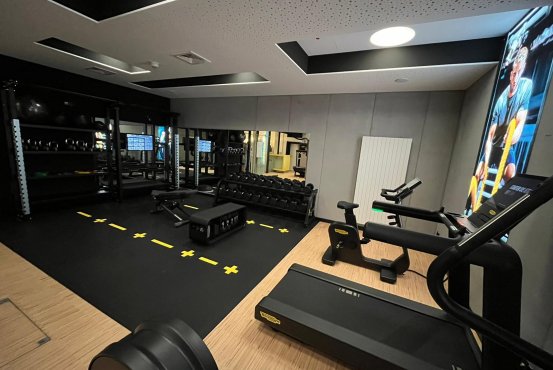 Fitnessstudio mit Premium-Ausstattung – Hotel Schloss Montabaur Fitnessstudio im Hotel Schloss Montabaur mit Laufbändern, Hanteln, Spiegelwand und motivierendem Poster.