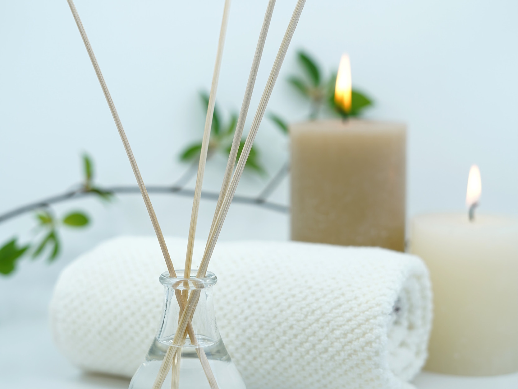 Wellness-Accessoires – Hotel Schloss Montabaur Wellness-Arrangement im Spa des Hotels Schloss Montabaur mit Duftstäbchen, Kerzen, Handtuch und grünen Akzenten.