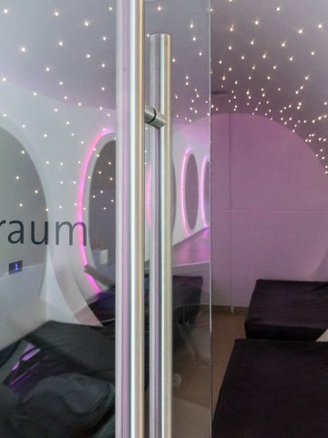 Ruheraum Spa – Hotel Schloss Montabaur Moderner Ruheraum im Spa des Hotels Schloss Montabaur mit schwarzen Liegen, runden Fenstern und Sternenlicht-Decke.