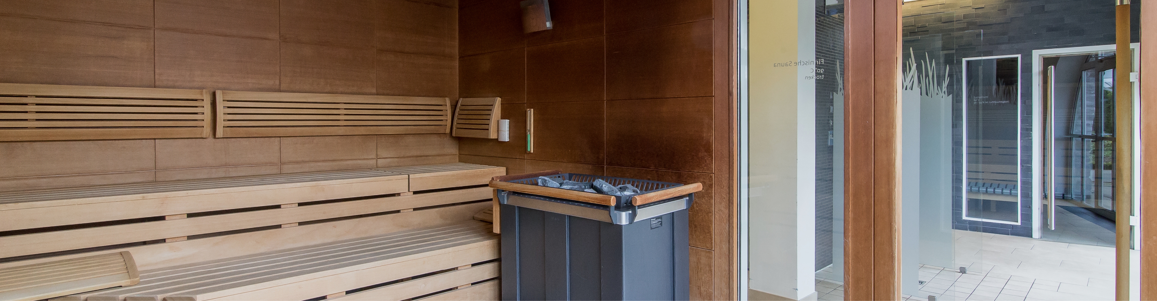 Sauna at the Spa – Montabaur Castle Hotel Modern sauna at Montabaur Castle Hotel Spa featuring wooden benches, steam stones, and a glass door to the relaxation area.