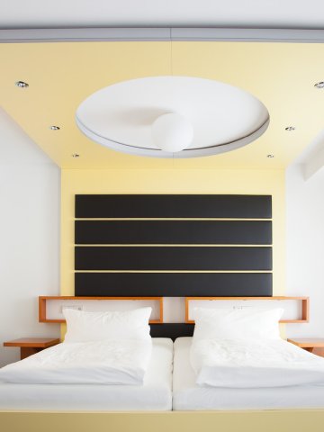 Bright economy room with functional design, cozy bed and walking desk at Hotel Schloss Montabaur